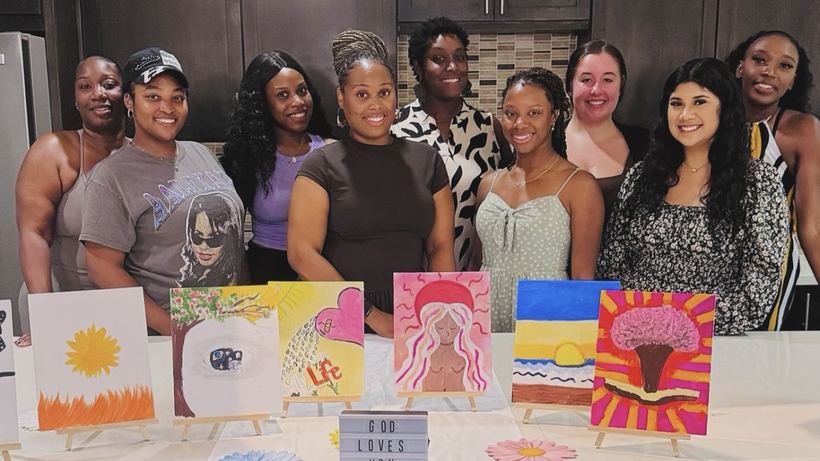 Guests holding up their finished canvases at Paint & Praise